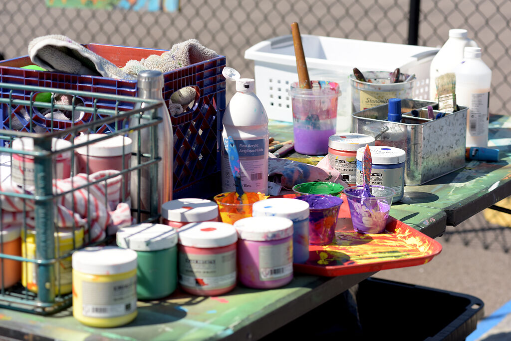 Acrylic paints and other supplies crowd a table